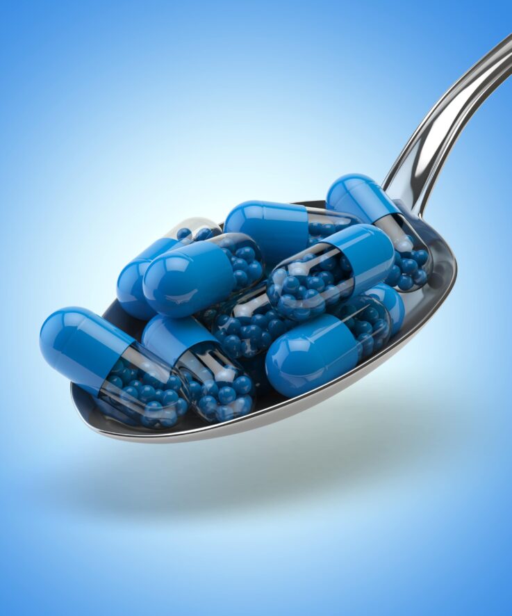 spoon-full-capsules-pills-blue-background-min spoon-full-capsules-pills-blue-background-min